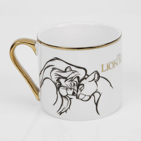 White porcelain mug with gold handle and rim, featuring a black line-art sketch of two nuzzling lions from The Lion King and gold title text, on a plain background.