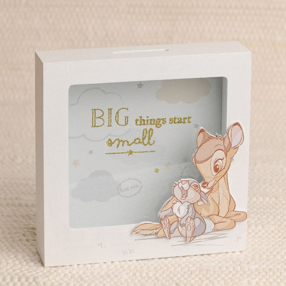 Square white money box with coin slot, featuring a raised cut-out of Bambi and a rabbit, pale grey cloud print, and "BIG things start small" in gold glitter text.