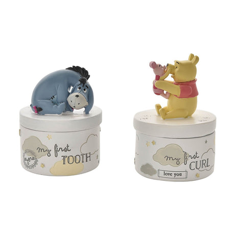 Round white keepsake boxes with cloud and star details, one topped with a curled Eeyore figure reading "my first TOOTH", the other with Pooh holding Piglet above "my first CURL".
