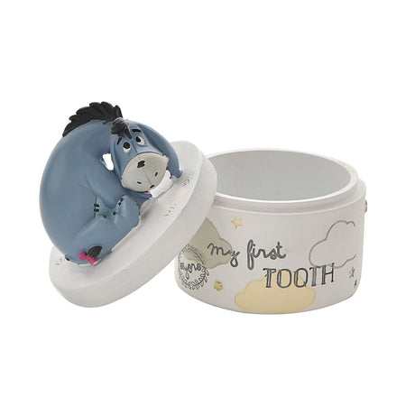 White round "my first TOOTH" keepsake box with Eeyore figure on the lift-off lid, decorated with grey and yellow clouds and stars on a plain background.