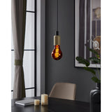 Dimmable LED filament bulb E27 in copper-toned glass with spiral filament, glowing warm white in a pendant fitting above a dark dining table.