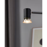 Dimmable LED GU10 5W bulb with clear faceted glass reflector lens, fitted to a black spotlight head on an adjustable arm in a softly lit room.