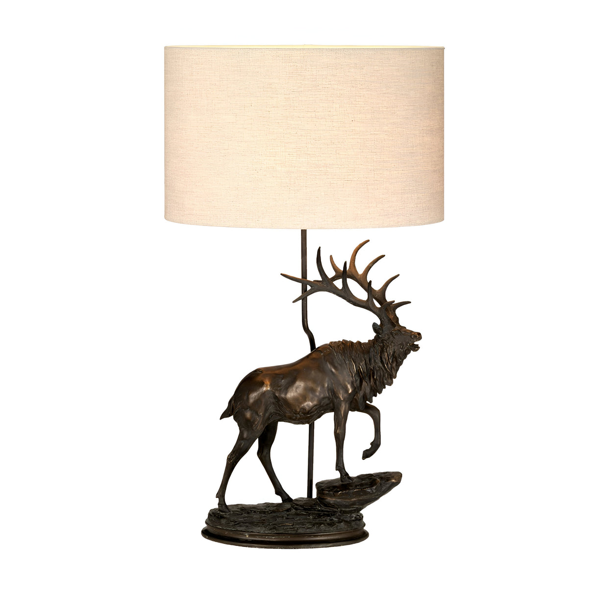 The Angus-2 Table Lamp with an oval shade in bronze patina features a sculpture of an elk standing on a rocky base. The detailed depiction of the elk's antlers offers a rustic, nature-inspired elegance to this piece.