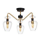 Introducing the Armand 3 Light Pendant Semi-Flush - Aged Brass Plated & Charcoal Black Paint: a modern ceiling fixture combining aged brass plated arms with charcoal black accents and clear glass shades, elegantly showcasing exposed bulbs. This design artfully merges industrial and contemporary styles, adding a sophisticated touch to any space.