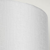 Close-up of the Cooper Medium Curved Wall Light in aged brass, featuring a minimalist white textured surface with rounded edges against a light grey background.