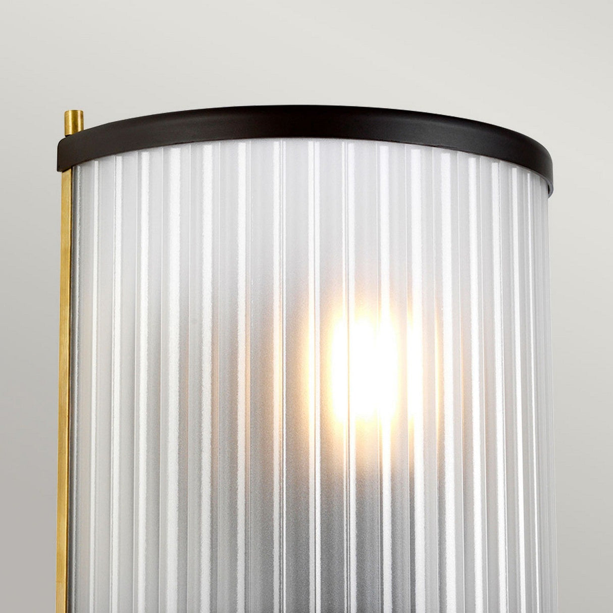 Here is a close-up of the Corona Wall Light - Dark Brown, featuring a ribbed glass shade that diffuses ambient light beautifully. This fixture has a brass and black metal frame with a dark brown finish, providing a modern and elegant look.