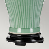 A detailed view of the Dalian Table Lamp With Tall Empire Shade - Celadon, showcasing its vertical ribbing design as it stands on a round black base, and featuring a smooth glossy finish reminiscent of Oriental ceramic vases.