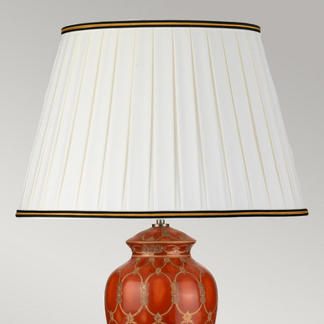 Introducing the Datai Table Lamp - Terracotta & Gold: This decorative table lamp features an intricate red terracotta base inspired by oriental ceramics, with a striking golden lattice design. It is complemented by a large pleated ivory cotton shade, elegantly finished with black and gold trim along the top and bottom edges.