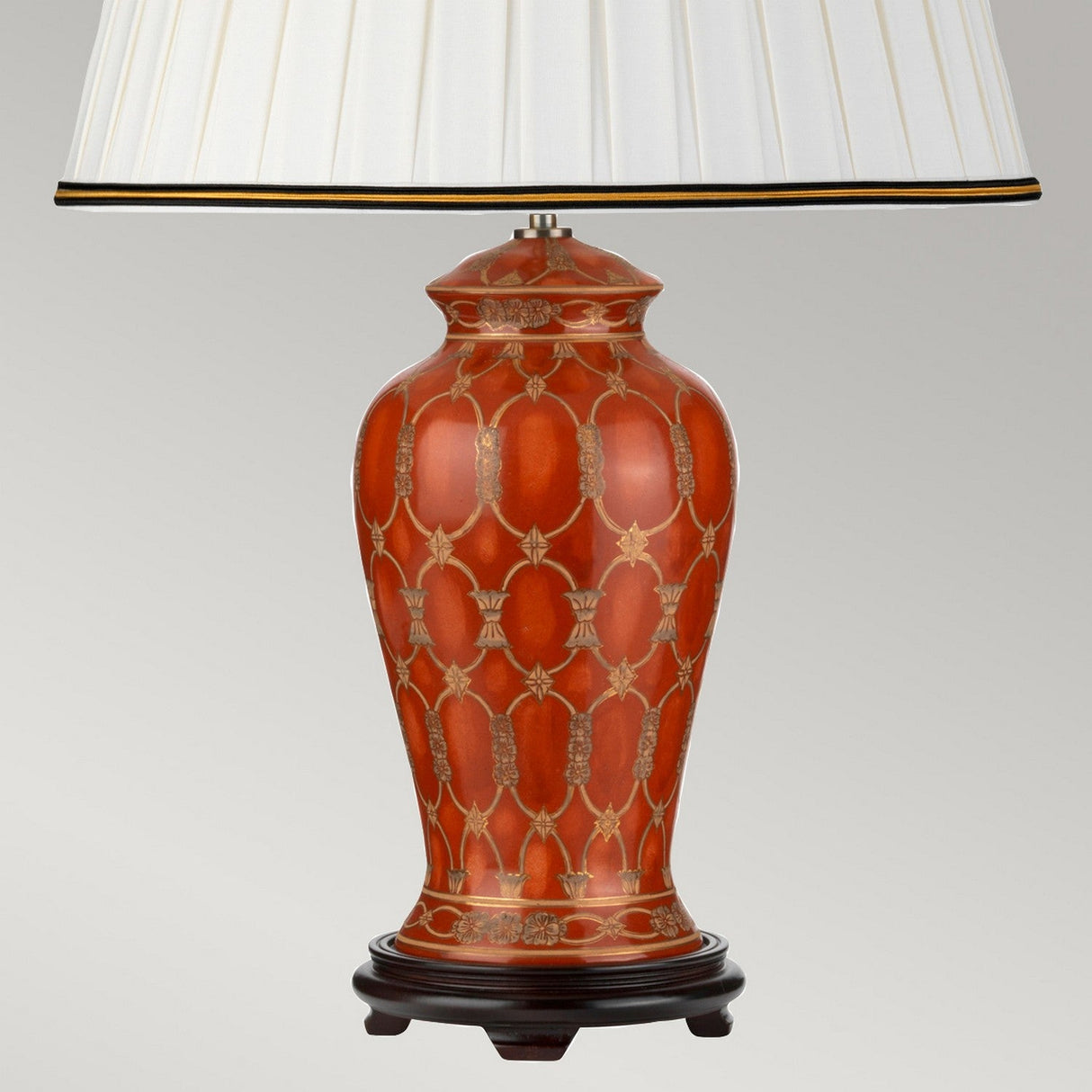 The Datai Table Lamp - Terracotta & Gold captures the essence of oriental ceramics with its terracotta and gold lattice pattern. It is complemented by an elegantly pleated ivory cotton shade, accented with a black trim. This exquisite lamp stands on a dark wood base, set against a plain gray background to create a striking yet subtle focal point in any space.