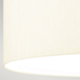 A close-up of the ivory shade made from faux silk, showcasing its smooth texture against a neutral background. The light is turned on, casting a warm and subtle glow over the lower part of the Fletcher 18" Flush Ceiling Fixture with an aged brass finish.