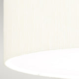 A close-up of the ivory shade from the Fletcher 26" Flush - Aged Brass fixture highlights its faux silk texture, featuring a subtle gradient from cream to bright white that showcases the fabric's weave pattern. The slightly curved bottom edge is set against a neutral gray background, adding a touch of elegance to any room when paired with the aged brass finish.