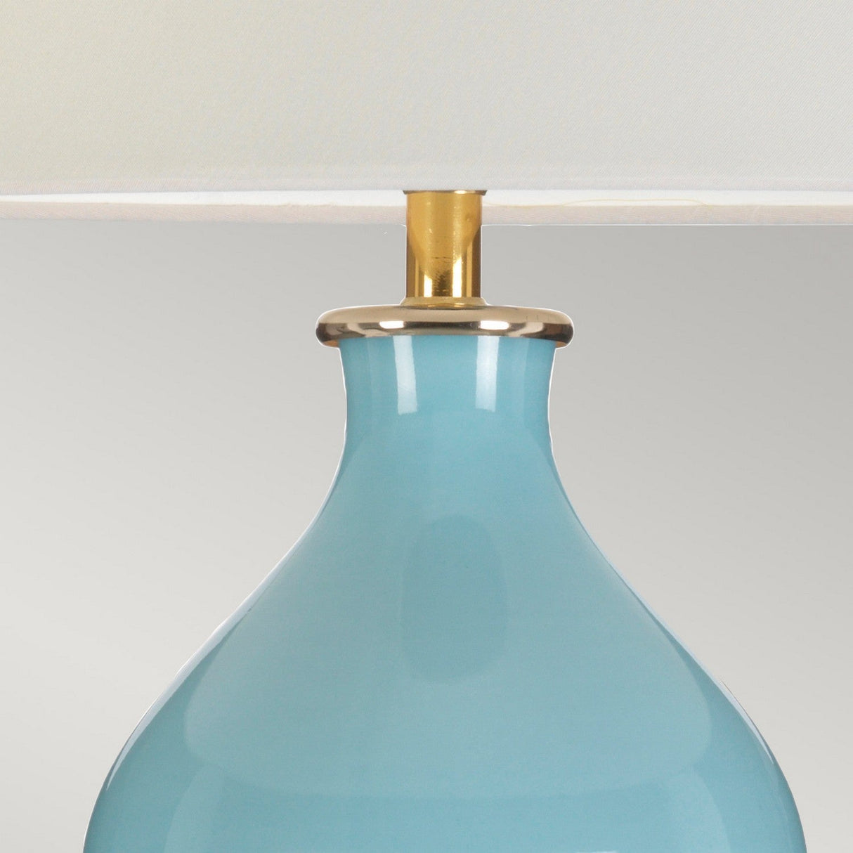 Close-up of the Harbin Gourd Table Lamp With Tall Empire Shade in Duck Egg Blue, showcasing its glossy ceramic base. The base is adorned with a gold-colored ring connecting to the shade, all beautifully set against a neutral light gray background.