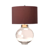 The Kara Table Lamp - Polished Nickel - Smoke Glass showcases an eye-catching smoke glass base complemented by a wide, cylindrical brown lampshade. Its polished nickel accents add to the sleek and modern aesthetic, making it ideal for contemporary interiors.