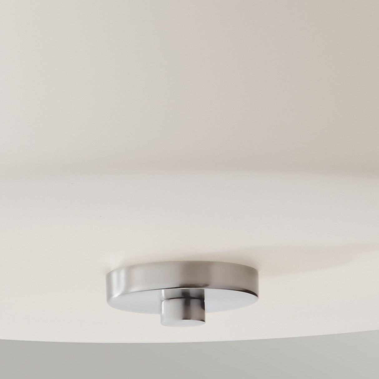 Close-up of the Kincaid 3 Light Flush - Polished Chrome, showcasing its opal-etched glass and polished chrome base. The design boasts clean lines and a central metal accent, embodying a minimalist aesthetic ideal for those desiring a close-to-ceiling look.