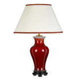 The Majin Table Lamp with Tall Empire Shade - Oxblood features a glossy red ceramic base with an oxblood finish, complemented by a red-trimmed empire shade and supported by a black circular stand.