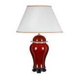 The Oxblood Temple Jar Table Lamp With Tall Empire Shade - Oxblood showcases oriental elegance with its curved, glossy red ceramic base that commands attention. It is complemented by a white, tapered lampshade with a gold-trimmed edge, standing gracefully on a small black platform.