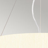 A close-up of the Pearce 18" Pendant Light, featuring a textured ivory shade set against a light gray backdrop, highlights its modern design. Two wires, one white and one brown, rise from the top of this elegant pendant fixture in polished chrome.
