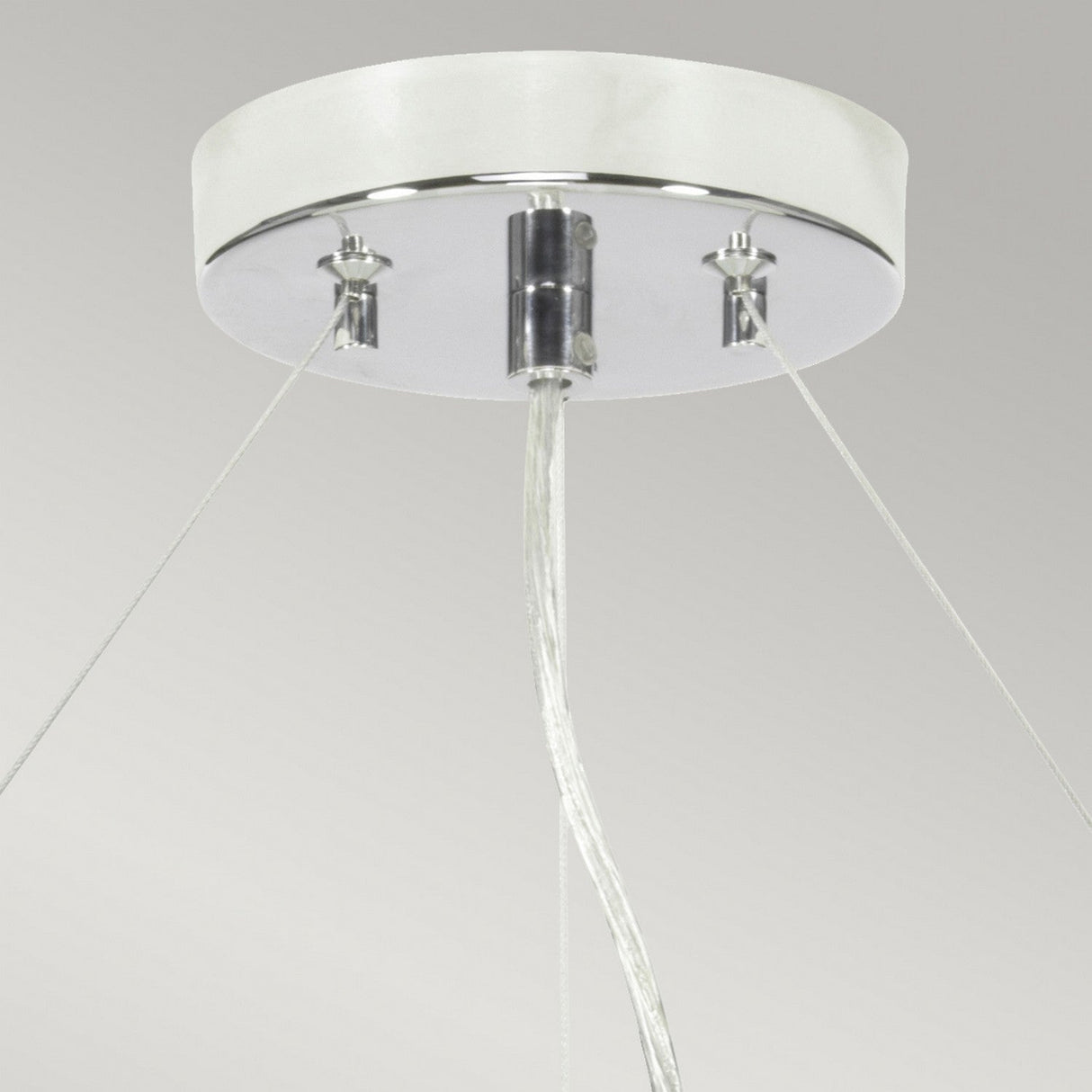 Close-up view of the Pearce 26" Pendant Light featuring a polished chrome finish and an ivory shade. Three clear wires extend from the round white base, complementing the sleek aesthetic of modern interiors. The background is a plain light gray, highlighting the fixture's elegant design.
