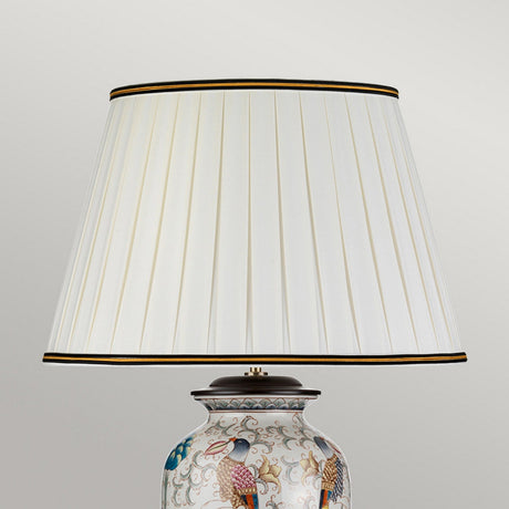 Introducing the Ping Table Lamp, featuring a base crafted from porcelain with hand-painted birds, including vibrant peacocks and floral patterns. It boasts an ivory cotton box pleat shade and mirrors the elegance of a cream-colored oriental vase against a neutral backdrop.