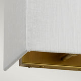 Close-up of the Riley Small Rectangular Wall Light in Aged Brass, showcasing a fabric-covered corner with a faux silk shade. The aged brass base provides a smooth metallic finish and includes a small toggle switch for convenience.