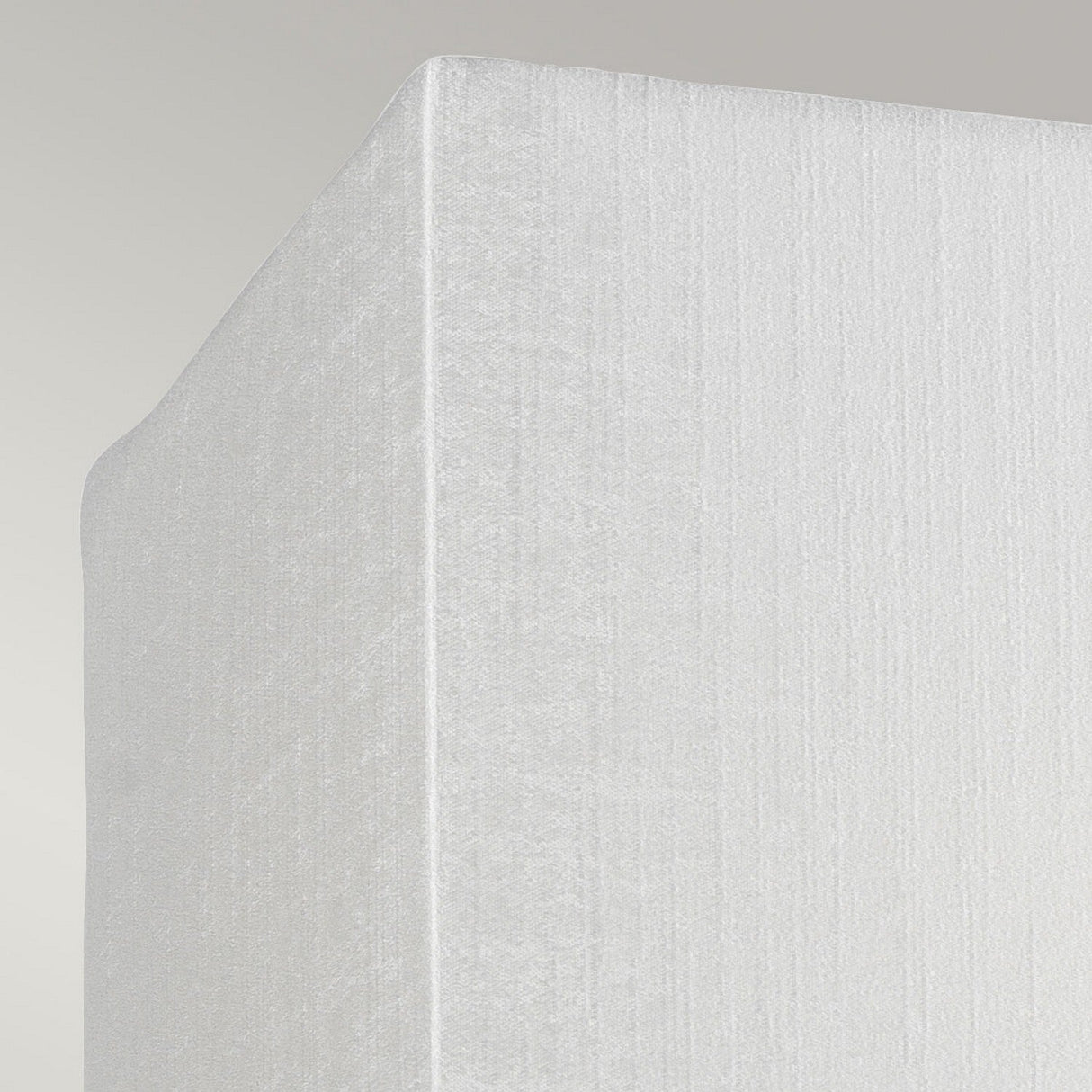 Close-up view of the corner of a textured white mattress set against a light gray background, subtly illuminated by the Riley Small Rectangular Wall Light in Polished Chrome, which casts gentle shadows.