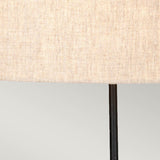 Close-up of the Spirit Table Lamp With Oval Shade - Bronze Patina, showcasing a neutral-colored fabric lampshade with a subtle woven texture atop a slender, black metal lamp stand with a bronzed finish, set against a light gray background. Ideal for infusing elegance into any space for both equestrian enthusiasts and design lovers.