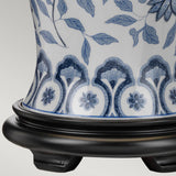 Close-up of the Ying 1 Light Table Lamp in blue and white, featuring classic Chinese floral patterns and intricate designs on a white background. The lamp is elegantly positioned on a dark wooden stand with a smooth, curved base, beautifully illuminated by ambient lighting.