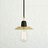 Doon Brass Pendant Light with a shallow, wide-brimmed polished brass shade, black ceramic lampholder, exposed bulb, and black cable, shown against a plain patterned white background.