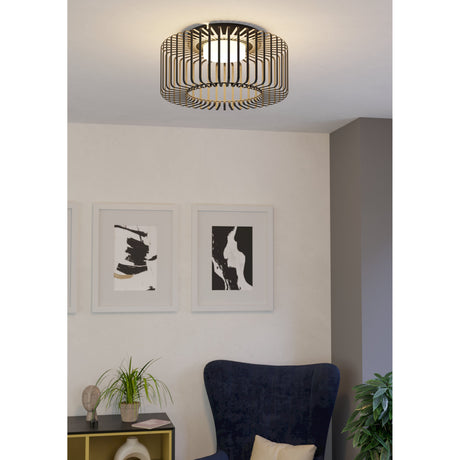 Dosmorne Smart Colour Changing LED ceiling light with black steel slat cage and white diffuser, shown mounted above a living room with armchair and framed art.