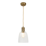 The Douille 1 Light Pendant in aged brass features a gracefully suspended design with a twisted cord. Its clear ribbed glass shade reveals an exposed bulb, beautifully complemented by LED filament lamps, creating an elegant and timeless look.