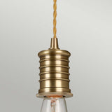 The Douille 1 Light Pendant in Aged Brass showcases a vintage design with ribbed detailing and a twisted fabric cord. Its exposed LED filament lamp adds to its retro charm, seamlessly merging classic and modern styles.