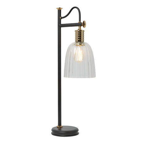 Presenting the Douille Table Lamp in Black & Polished Brass: a chic table lamp featuring a black metal base and arm, complete with a clear ribbed glass shade and polished brass bulb socket. It casts a warm glow that brings to mind classic vintage style.