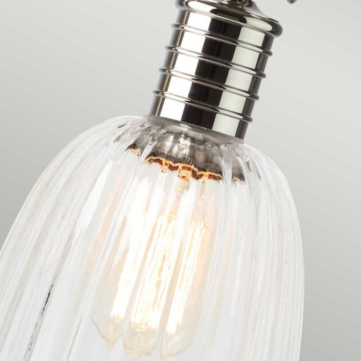 Close-up of a vintage-style LED filament bulb featuring a ribbed glass cover and polished nickel fixture. The bulb is illuminated, casting a warm glow against a soft grey background, reminiscent of the elegant design of the Douille Table Lamp - Polished Nickel.