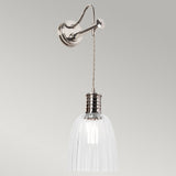 The Douille Wall Light - Polished Nickel is a wall-mounted fixture that features a metallic arm and clear glass shade. The ribbed glass texture and vintage-inspired charm are highlighted by a visible bulb, suspended by a twisted cord, all complemented by a neutral gray backdrop that enhances its timeless elegance.