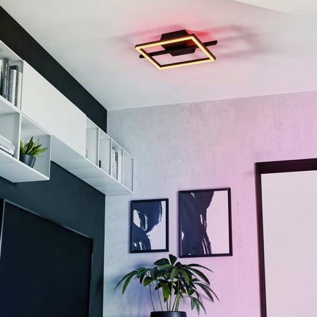 Dralena 40cm square flush LED ceiling light in black with an open frame design, shown glowing red on a white ceiling in a living room with shelving and framed artwork.