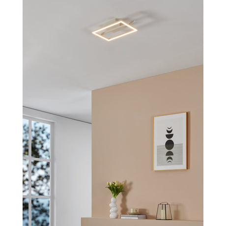 Dralena 40cm white flush ceiling light with open square frame and crossbar, illuminated warm white, mounted on a hallway ceiling beside a pink wall with framed artwork.
