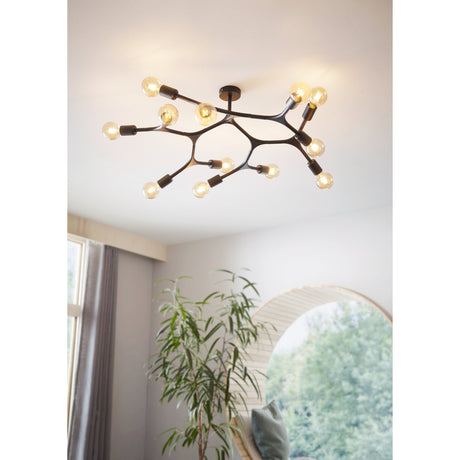 Dramenne 12 Light Ceiling Light in black steel with branching arms and exposed bulbs, shown mounted on a white ceiling above a bright living room with plants and a window.