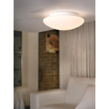 Drasmena Flush Ceiling Light 20cm in white, with domed opal glass shade and white steel base, shown illuminated on a ceiling in a living room setting.