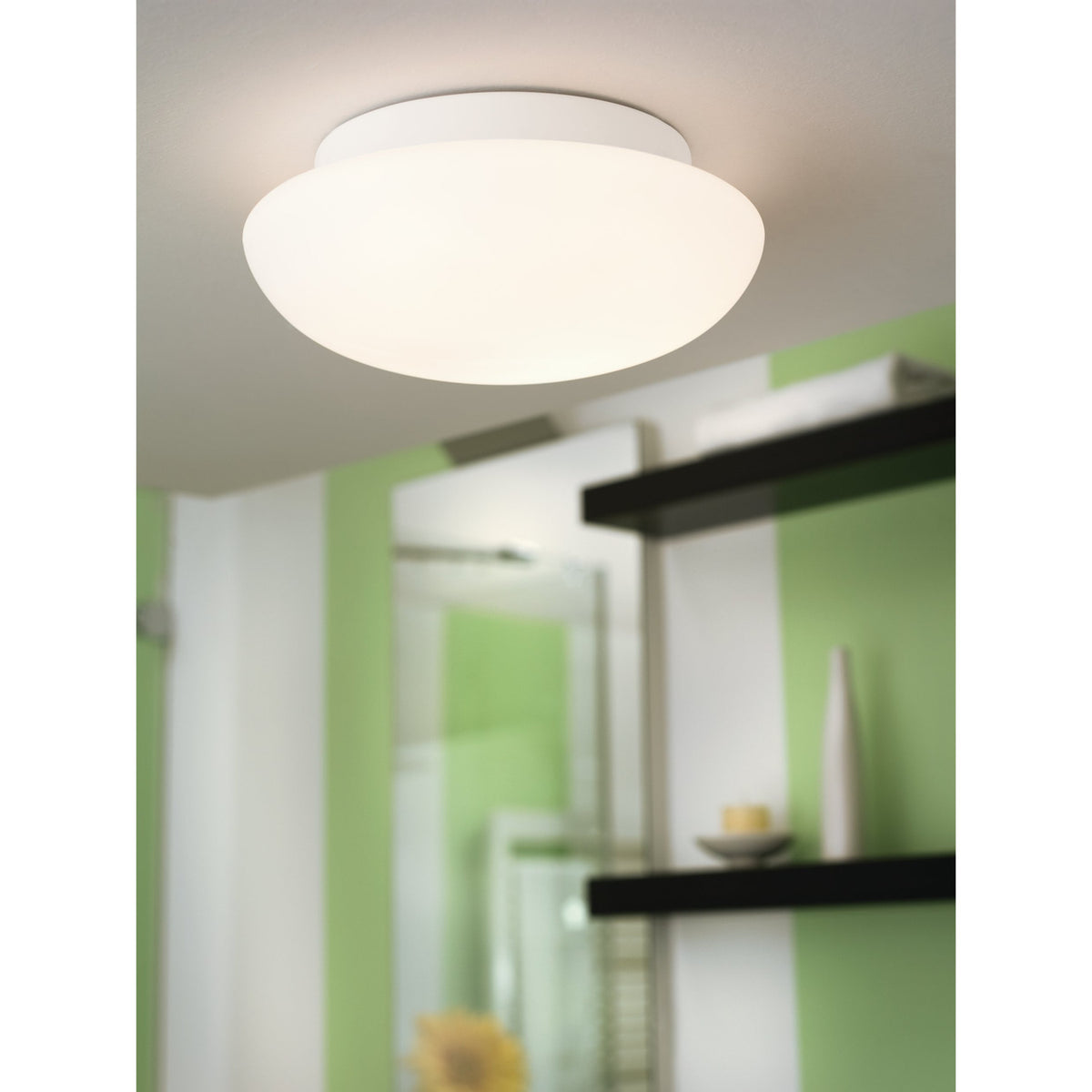 Drasmena 28cm flush ceiling light with white steel plate and domed opal glass shade, shown illuminated on a hallway ceiling near green and white walls.