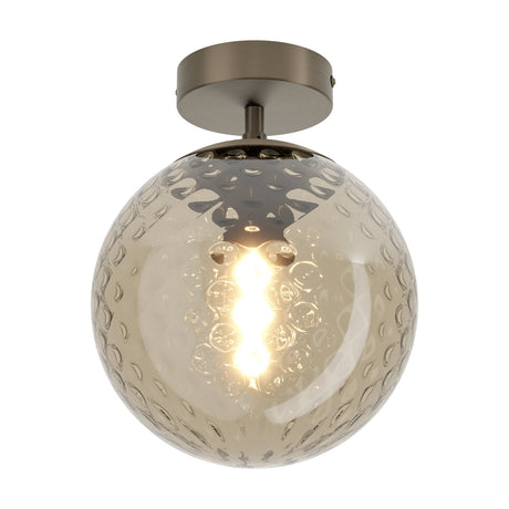Drilvenne semi-flush ceiling light with a dimpled smoky brown glass globe on a dark bronze steel ceiling plate and short stem, shown lit against a plain white background.