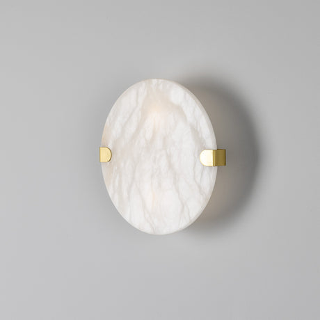 Dundee Alabaster Twin Wall Light IP44, a round white alabaster disc wall light with brass clips and backplate, glowing softly, shown against a plain grey background.