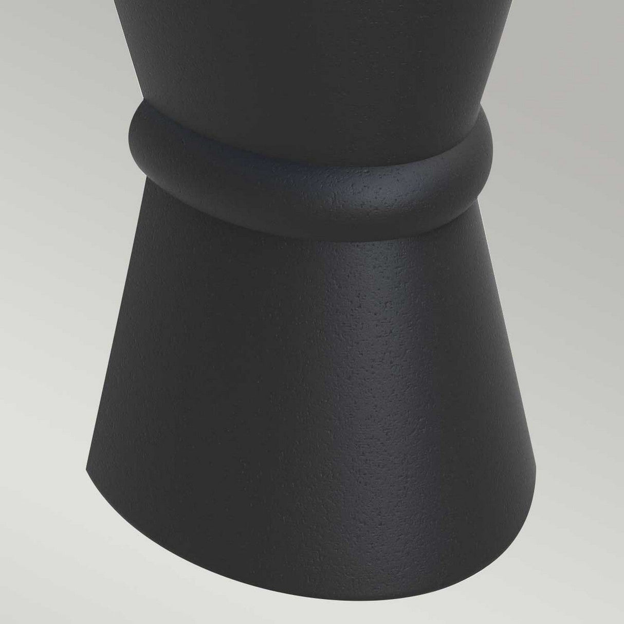 A close-up of the Dungarvan 2 Light Outdoor Up & Down Wall Light in black, featuring a textured cylindrical shape with a flared end and an elegant ring-like detail near the top. Highlighting its UV resistance, it sits on a light grey surface, showcasing its ideal suitability for outdoor lighting applications with its corrosion-proof design.