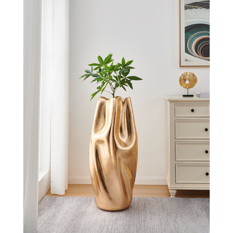 Dunnamore Plant Pot 100cm in Gold, a tall fibreglass floor planter with draped, fold-textured sides and a wavy rim, shown holding a green plant in a living room setting.