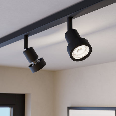 Easyt Spot Ring track spotlights in black plastic with slim stems and cylindrical bodies, ring-shaped heads holding GU10 bulbs, mounted on a black ceiling track in a room setting.