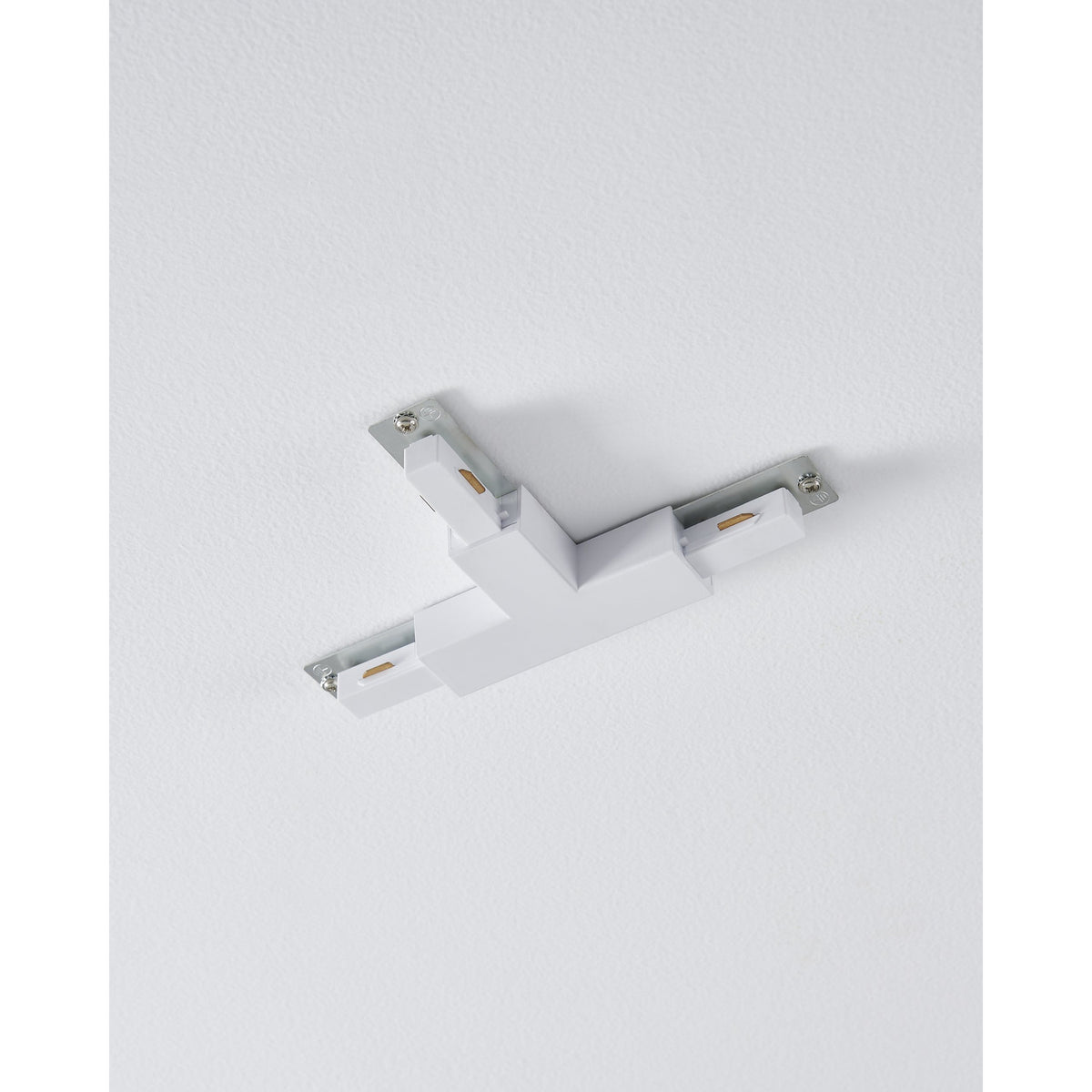 Easyt Track T Connector in white plastic, a three-arm T-shaped joiner with silver mounting plates, screws and brass contact tabs, shown mounted on a plain ceiling.