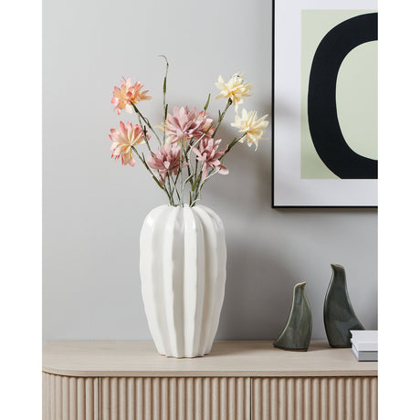 Egele Ceramic Vase in glossy white with deep ribbed sides and a zigzag rim, styled with pink and cream flowers on a wooden sideboard beside framed artwork.