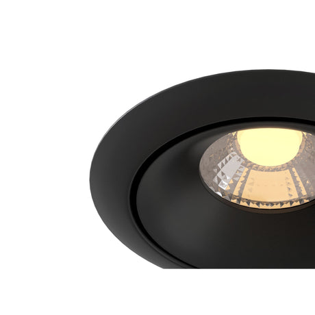 A close-up of a Yin LED Round Recessed Downlight 9W 3000K - Black highlights its black trim and glowing bulb, featuring a textured reflector that casts warm light against a plain white background.