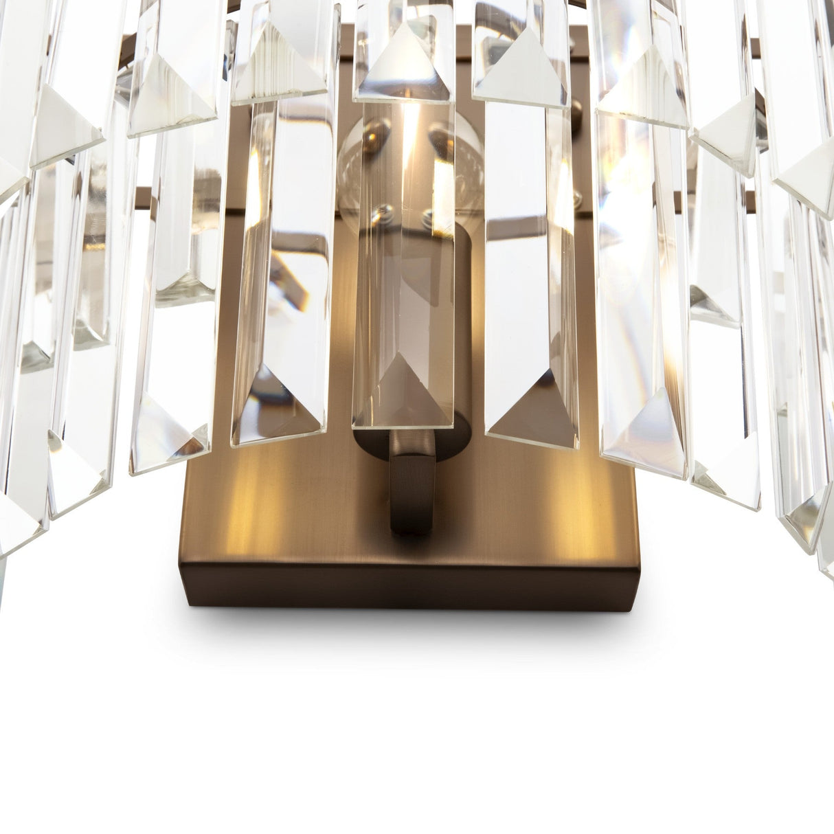 The Revero Classic Wall Light features elongated rectangular transparent glass prisms vertically arranged on a polished brass fixture, casting a sparkling effect against a white background.