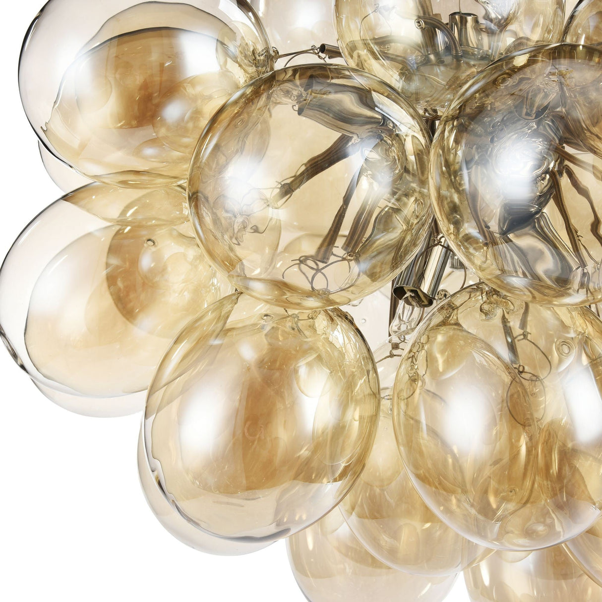 A close-up of the Balbo 8 Light Chandelier - Nickel With Cognac Glass shows a cluster of translucent, golden bubbles. Crafted from cognac glass, these spheres reflect light warmly, complemented by sleek nickel-finished metallic elements inside.