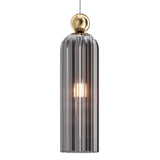 The Antic Pendant Light features a grey ribbed glass shade, a warm glowing bulb inside, and is elegantly anchored by a gold metal frame. A small, smooth metallic gold sphere connects it to the hanging cord.